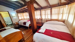 A hotel room with two beds, wooden flooring, and a wooden ceiling structure. - ANDENES DEL SOL (Cusco)