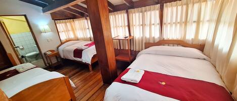 A hotel room with two beds, wooden flooring, and a wooden ceiling structure.