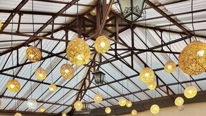 A restaurant with wooden tables and chairs, hanging spherical lights, and a high ceiling with metal beams. - ANDENES DEL SOL (Cusco)