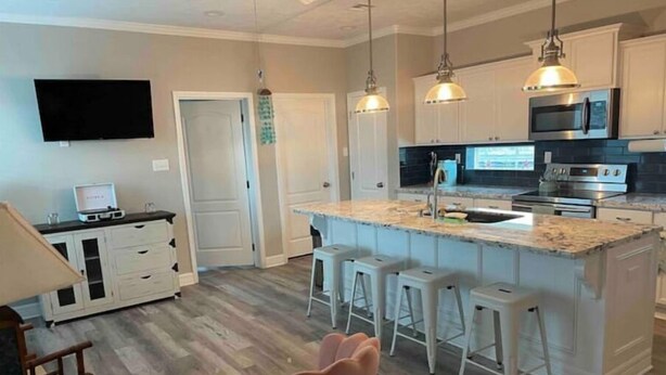 A modern kitchen with a central island, bar stools, and pendant lighting.