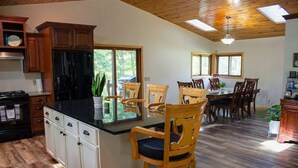 A kitchen with wooden cabinets, a black refrigerator, and a dining area with wooden chairs and a table. - Waterfront Peninsula Escape Cabin (Lakewood)