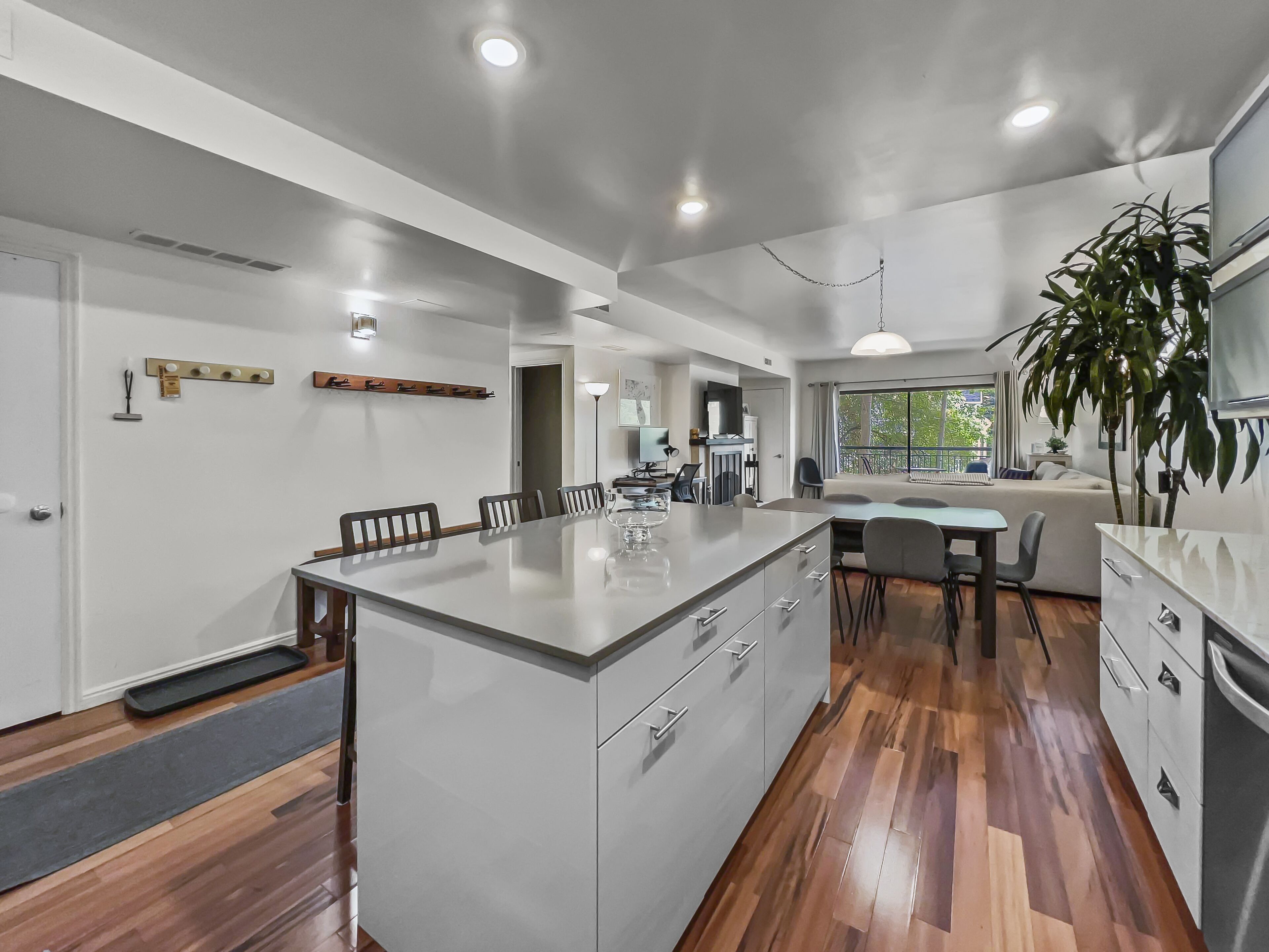 Una cocina moderna con una isla central, suelo de madera y vistas al exterior.