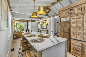 Una cucina moderna con un piano di lavoro in marmo, sgabelli di legno e illuminazione a sospensione.