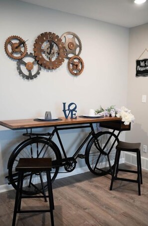 Enjoy meals at the unique bicycle table with two chairs, accompanied by a decorative gear wall hanging.