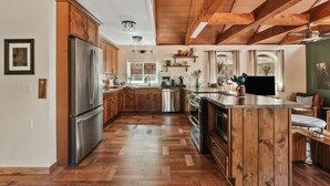 A spacious kitchen with wooden cabinets, a stainless steel refrigerator, and a wooden island.