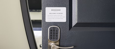 Una puerta negra con cerradura electrónica y un letrero encima.