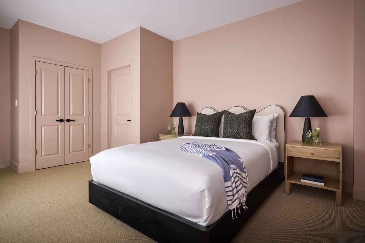 A bedroom with a bed, two bedside tables, a nightstand, and a door.