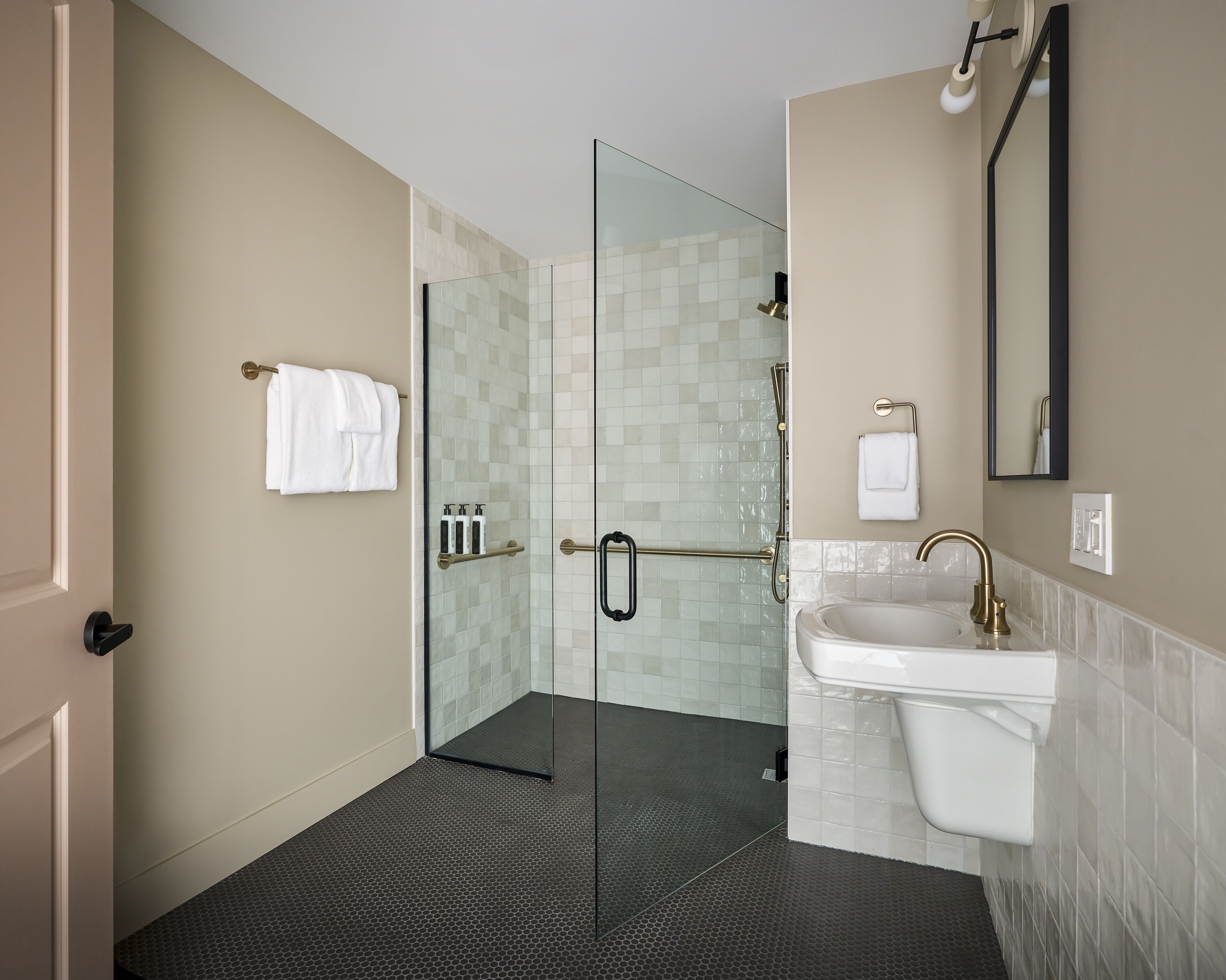 A modern bathroom with a glass shower enclosure, a white sink, and a large mirror.