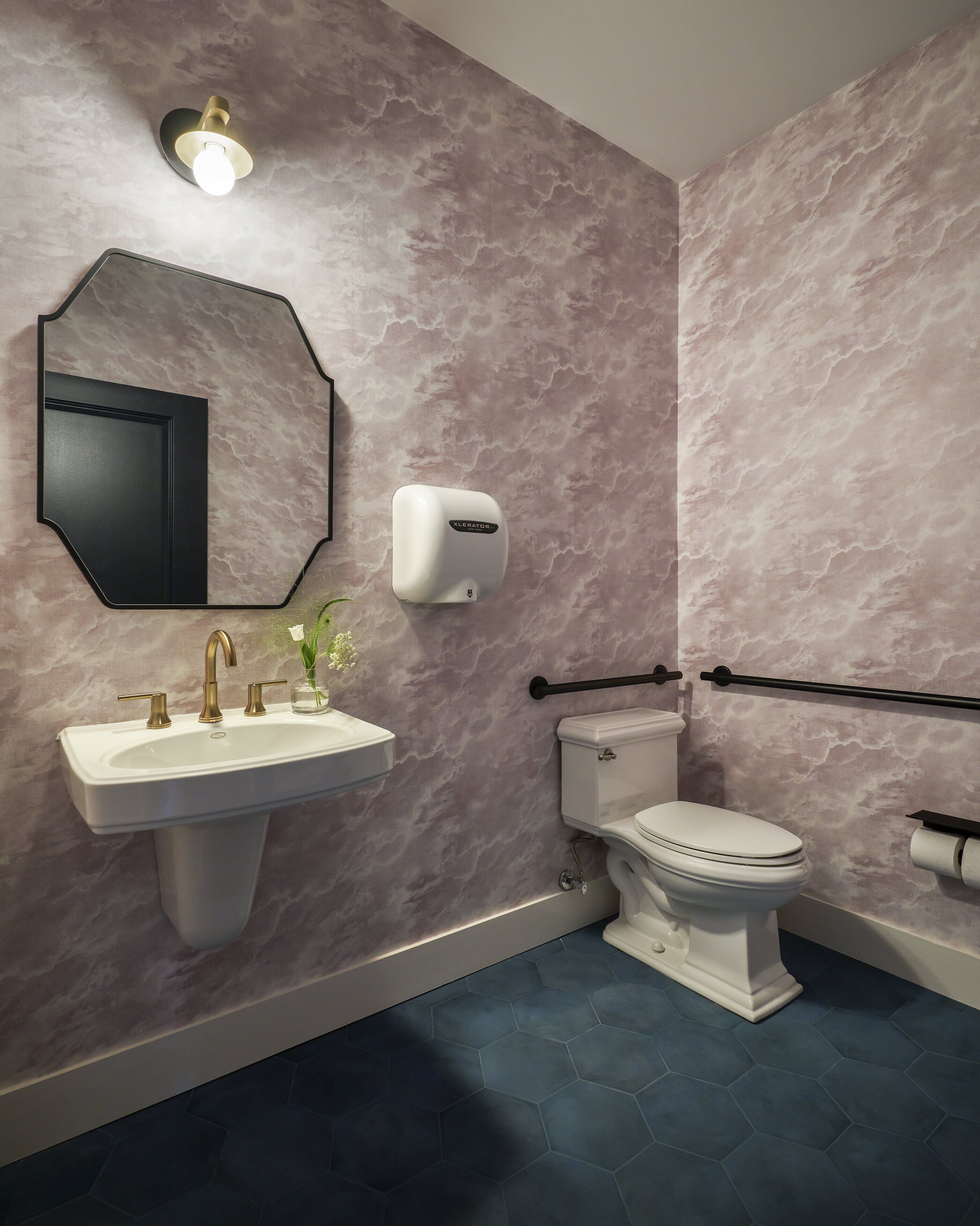 Un baño con lavamanos blanco, inodoro y dispensador de jabón.