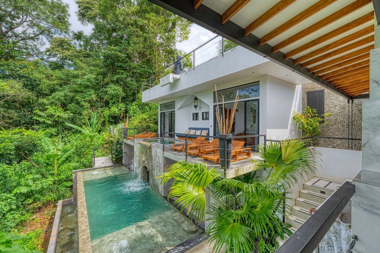 Ein modernes Haus mit Schwimmbad, umgeben von üppiger Vegetation.