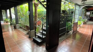 Un espacio al aire libre cubierto con suelo de baldosas, una escalera con barandillas de metal y plantas en macetas.