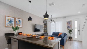 Une cuisine moderne dotée d’un îlot central, de meubles de couleur noire et d’un coin repas avec un canapé bleu.