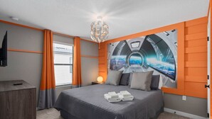 Une chambre à coucher avec un lit, une table de chevet, une lampe et un téléviseur fixé au mur.