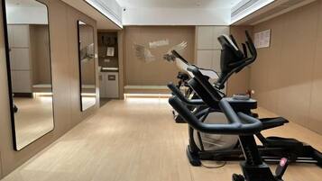 Une salle de sport équipée de matériel d’exercice, dotée d’un grand miroir et d’un mur orné d’un motif représentant des ailes.