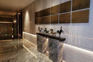 Un hall de entrada con mostrador de recepción de mármol, una obra de arte colgada en la pared y un diseño de pared estampado.