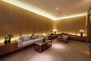A modern living room with a sofa, coffee table, and dining area. - Golden Splendid Hotel (Zhanjiang)