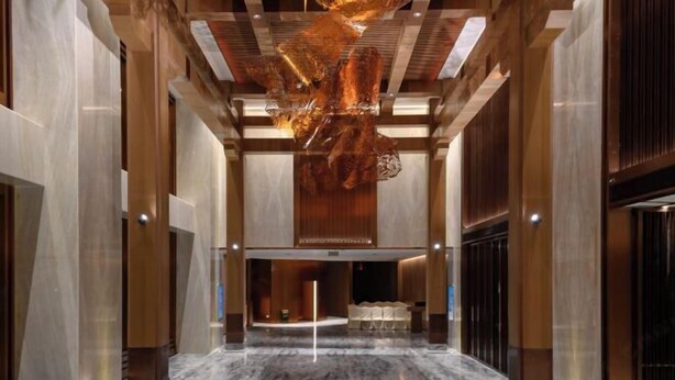 Un hall d’entrée spacieux, doté d’un sol en marbre, d’un lustre central et d’un comptoir de réception.
