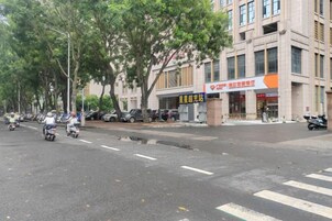 Una calle con árboles, coches aparcados y un edificio con un letrero.