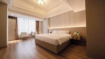 A hotel room with a large bed, a bedside table, a chair, and a window with curtains.