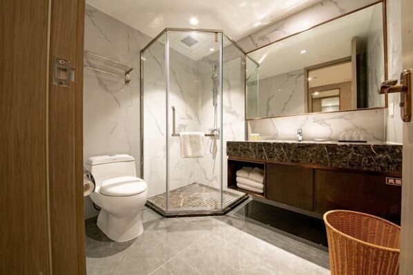 A modern bathroom with a glass-enclosed shower, a toilet, a marble-topped vanity, and a large mirror. - Golden Splendid Hotel (Zhanjiang)