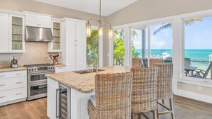 A kitchen with a large island, white cabinetry, stainless steel appliances, and a view of the ocean. - P04 - Beach Front Estate with Pool and 6 bedrooms (Marathon)