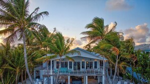 A beachfront house with a covered porch, outdoor seating, and palm trees. - P04 - Beach Front Estate with Pool and 6 bedrooms (Marathon)
