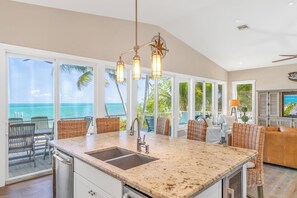 A kitchen with a large island, a sink, and a view of the ocean.