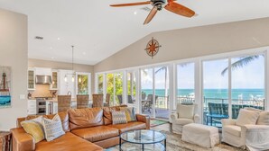 A spacious living area with a leather sofa, a glass coffee table, and a view of the ocean through large windows. - P04 - Beach Front Estate with Pool and 6 bedrooms (Marathon)