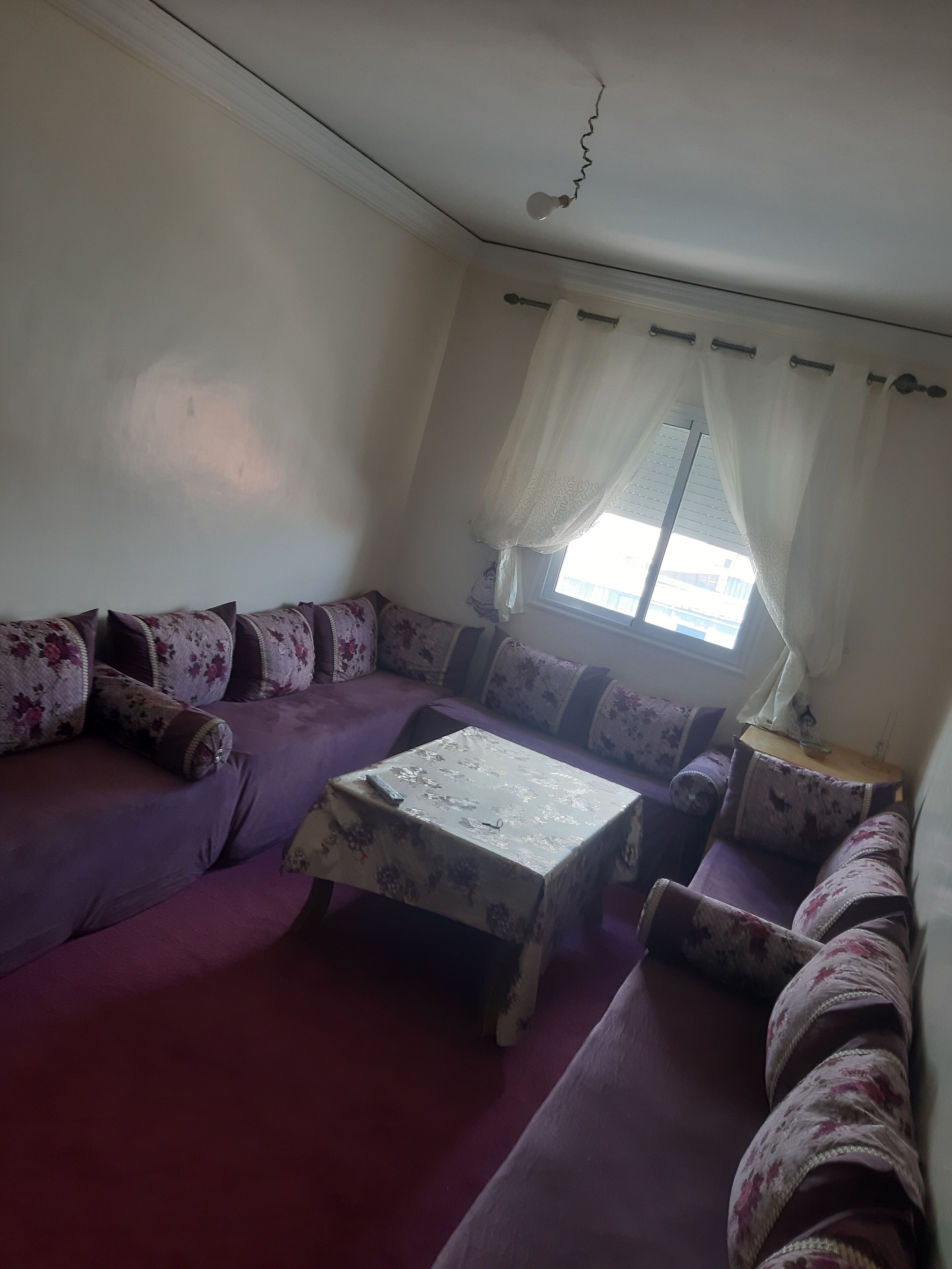 A living room with a sofa set, a coffee table, and a window with curtains.