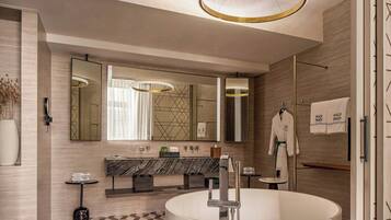 Un baño moderno con una bañera independiente, un espejo grande y un piso con diseño geométrico.