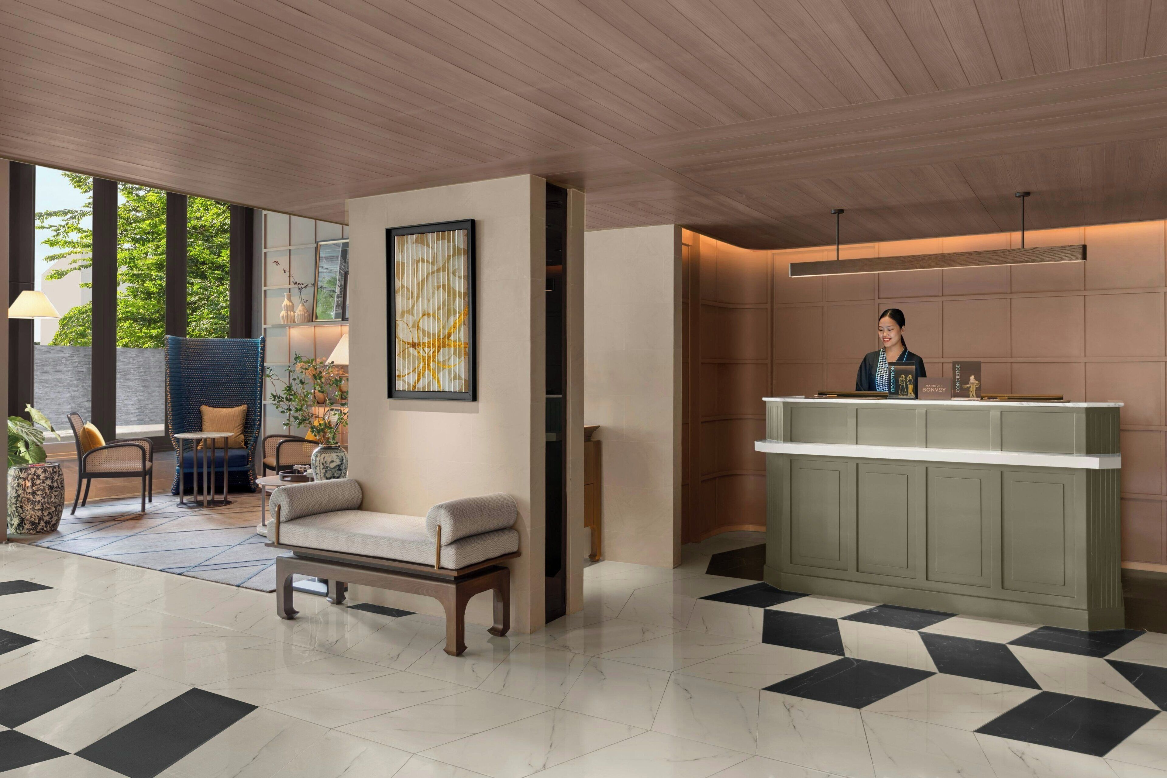 A modern lobby with a reception desk, seating area, and large windows.