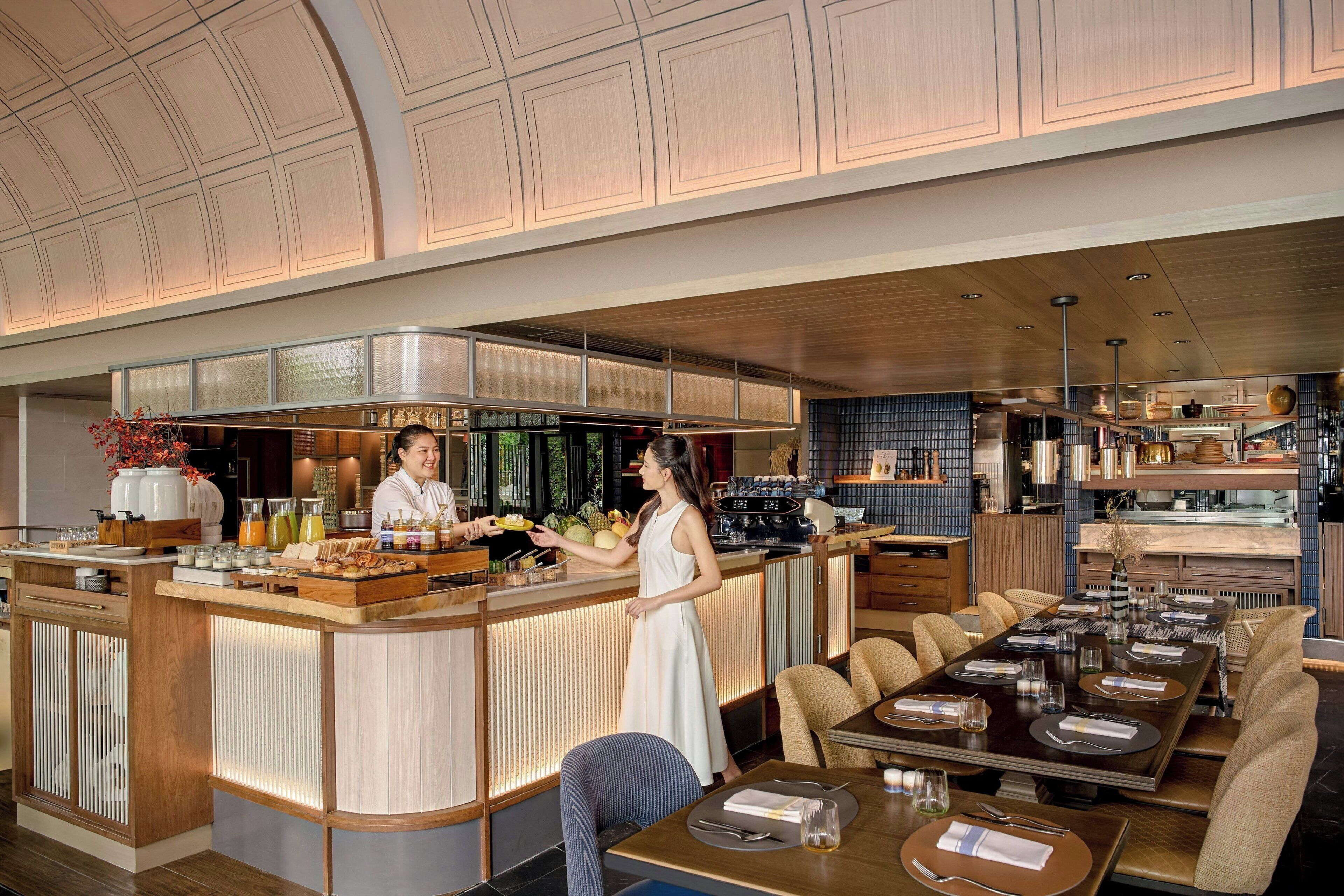 Un restaurant moderne doté d’un bar, de lambris en bois et d’un espace aménagé pour accueillir les clients.
