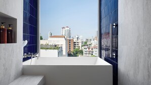Un bagno moderno con una vasca, una finestra e vista sulla città.