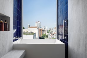 A modern bathroom with a bathtub, a window, and a view of a cityscape. - Madi Paidi Bangkok, Autograph Collection (Marriott International)  (Bangkok)