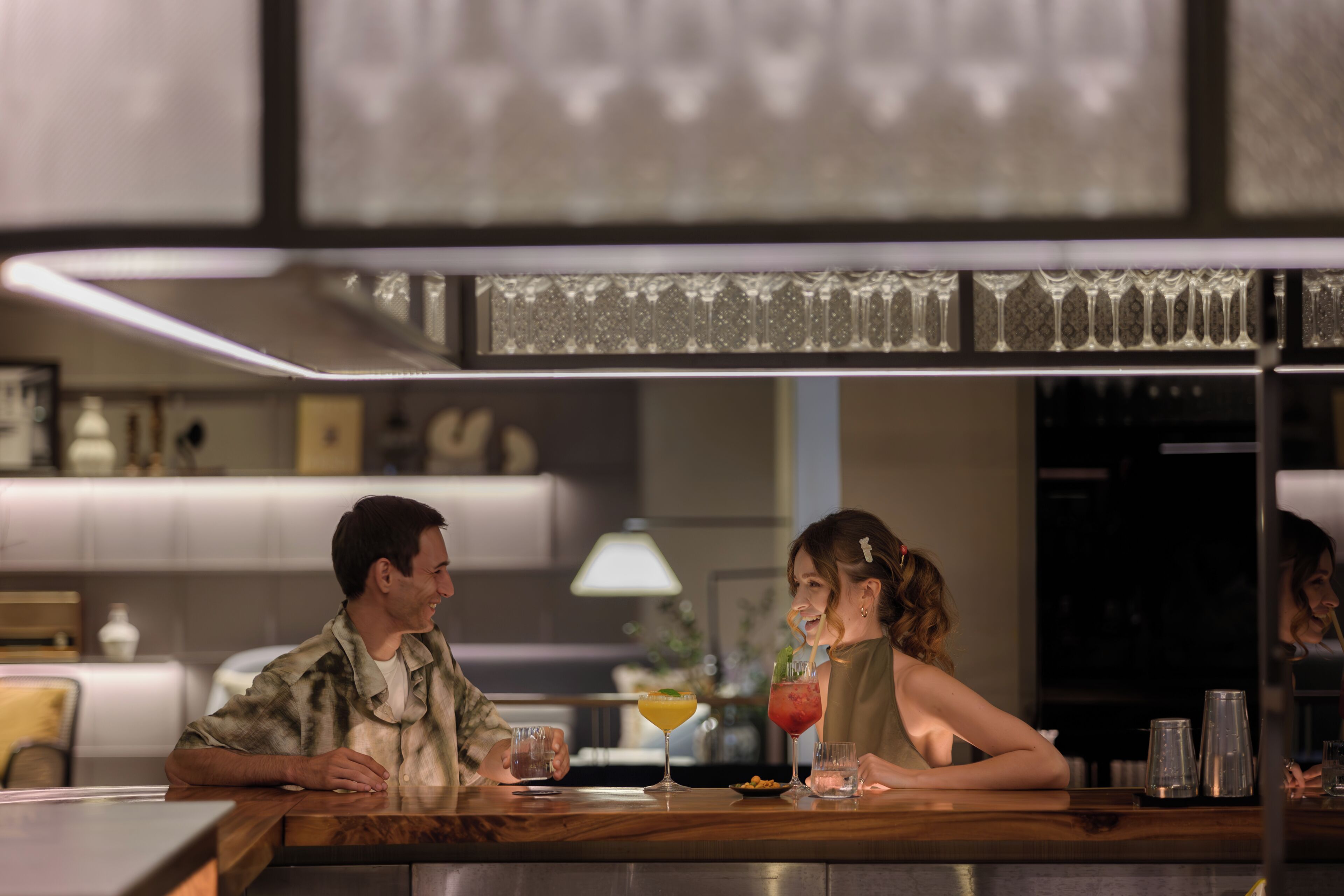 A bar area with a counter, glasses, and a bottle.