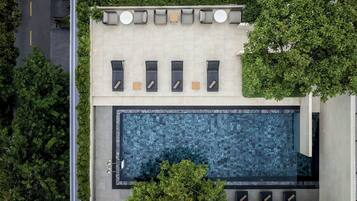 Vue aérienne d’un bâtiment moderne doté d’un espace de détente sur le toit, d’une piscine et d’un espace vert environnant.