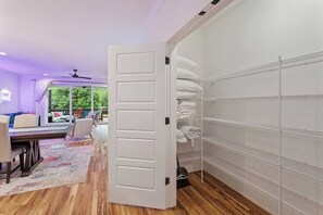 Una habitación con suelo de madera, una puerta blanca y una estantería con toallas dobladas.