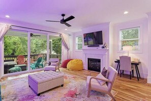 A living room with a fireplace, a television, and a balcony with outdoor furniture. - Near Carter‑Finley - Spacious Raleigh 4BR House (Raleigh)
