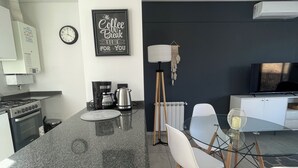 Una cocina moderna con encimera de granito, una cafetera y un reloj en la pared.