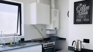 Una cocina moderna con armarios blancos, una estufa a gas, una cafetera y un cartel que dice 'The Coffee Break Time For You'.