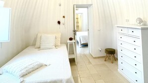 Ein Schlafzimmer mit Bett, Schminktisch, Nachttisch und einer Tür zu einem anderen Raum.