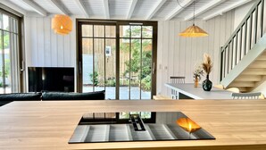 A modern kitchen with a large island, sliding glass doors to a patio, and a staircase with a railing.