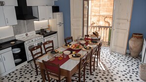 A kitchen with a dining table set for a meal, equipped with a stove, oven, and various kitchen appliances. - B&B U'Panare, in Taranto's historic center a structure reminiscent of home (Taranto)