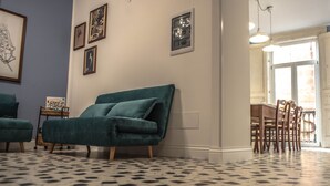 A living room with a teal sofa, a patterned floor, and framed artwork on the wall. - B&B U'Panare, in Taranto's historic center a structure reminiscent of home (Taranto)