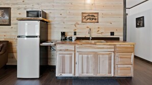 A compact kitchen with a wooden wall, a built-in microwave, a refrigerator, and a sink. - Lake Village Lodge (Coeur d'Alene)