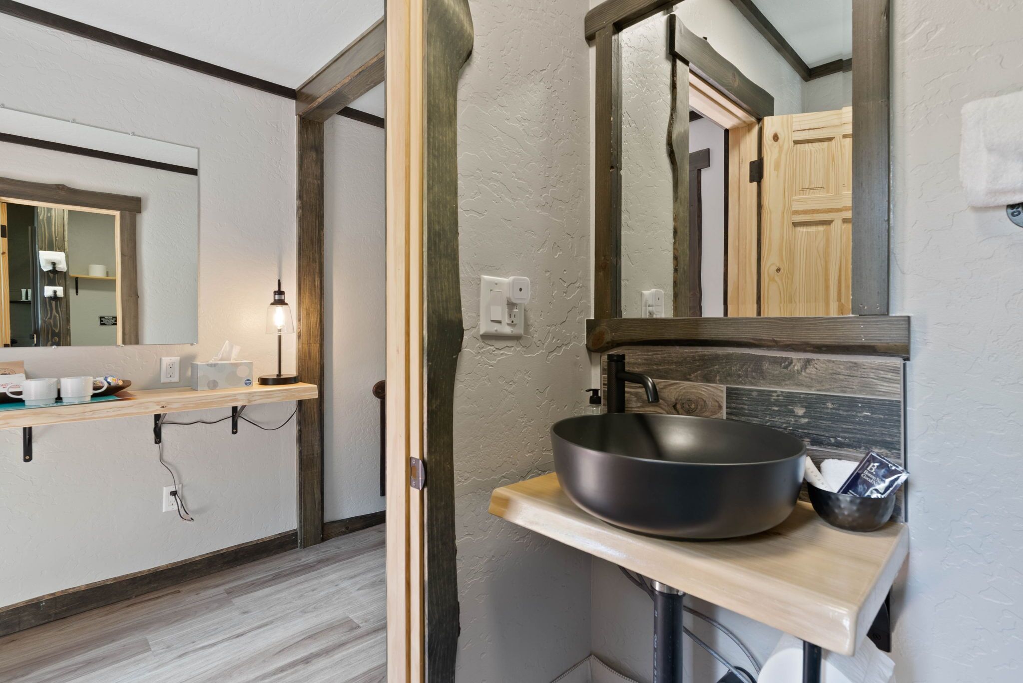 A bathroom with a wooden vanity, a large mirror, and a black basin.