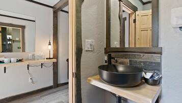A bathroom with a wooden vanity, a large mirror, and a black basin.