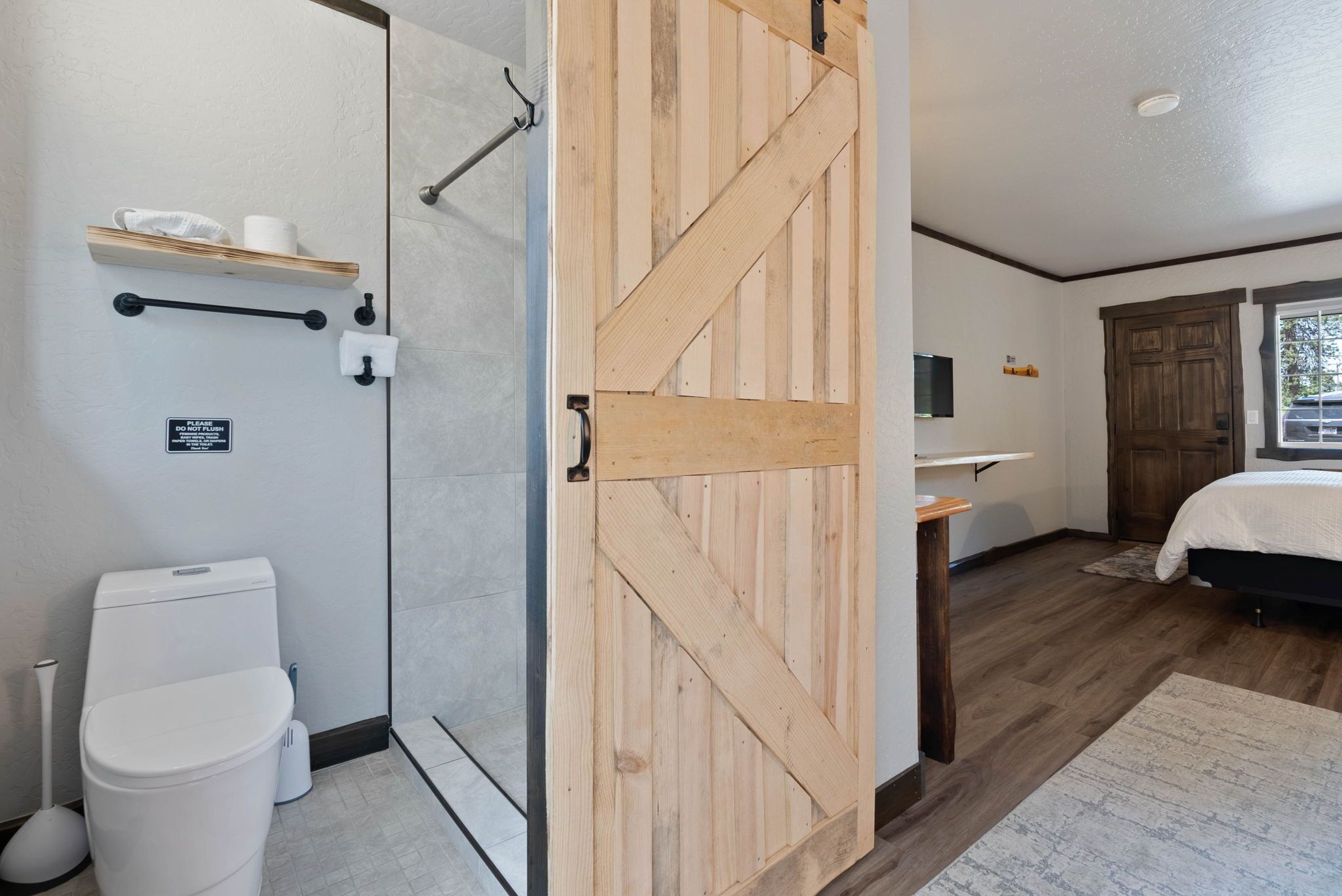 A bathroom with a shower, toilet, and a wooden door.