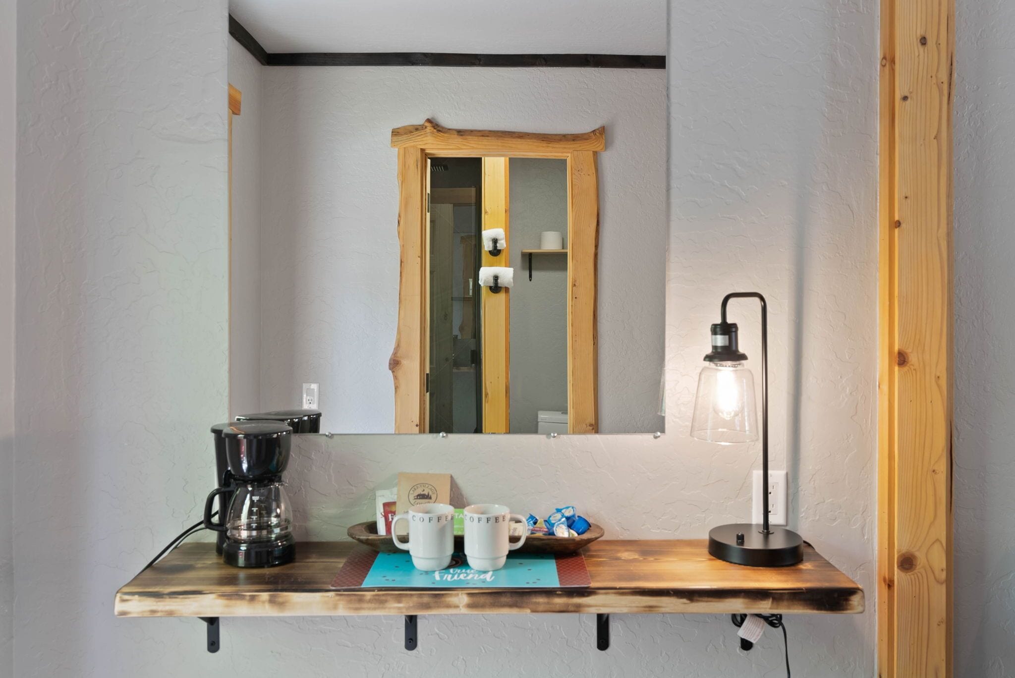 A wooden coffee table with a coffee maker, two mugs, and a tea bag box.