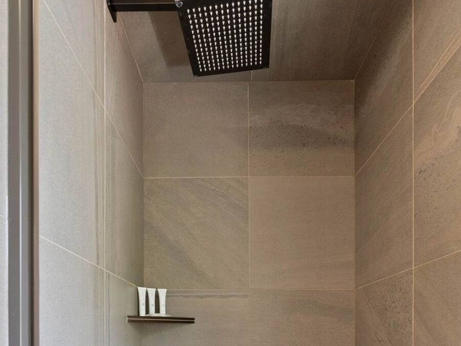A modern shower enclosure with a built-in shelf and a control panel.